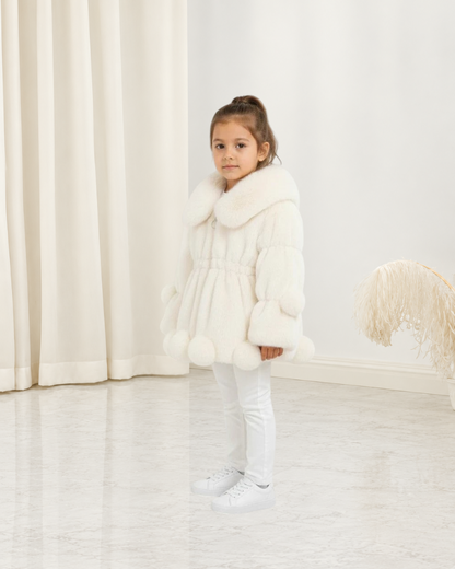 Jeune fille portant une veste en polaire blanche Le Cocon d'Or avec col à revers et détails à pompons